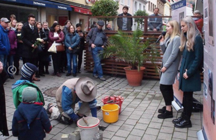 November 9, 2018: While Günter Demnig sets the Stolpersteine for the Zinn family, Julia Mehrmann and Antonia Voll from the P-Seminar "13 Driver's Licenses" present the biographies of the victims. In the background Mayor Andreas Hügerich.